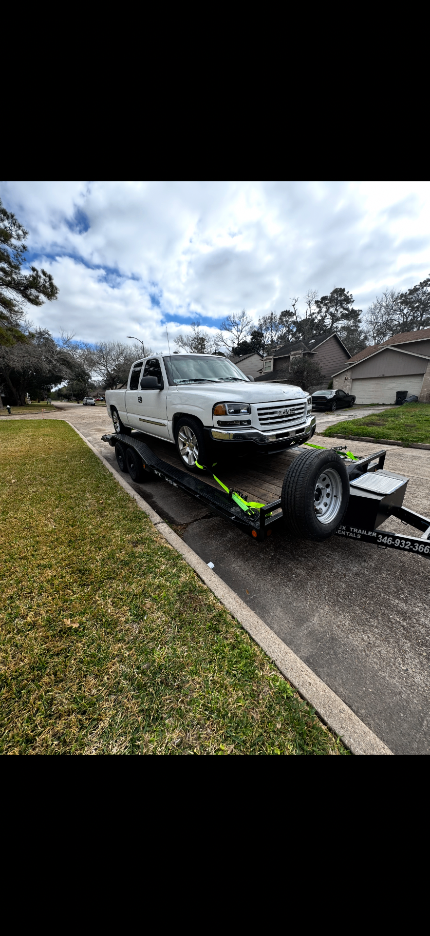 White GMC Sierra loaded on Eastex car hauler in residential driveway